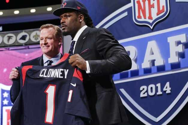 Jadeveon Clowney, defensive end de Carolina del Sur, sostiene un jersey de los Texans de Houston luego de ser la primera selección del draft de la NFL. A su lado el comisionado de la liga, Roger Goodell, el jueves 8 de mayo de 2014. (Foto AP/Craig Ruttle)