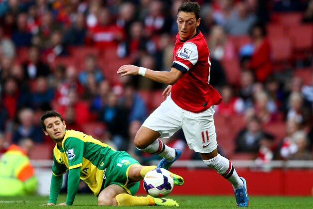 LONDON, ENGLAND - OCTOBER 19:  Mesut Oezil of Arsenal is tackled by Wes Hoolahan of Norwich City during the Barclays Premier League match between Arsenal and Norwich City at Emirates Stadium on October 19, 2013 in London, England.  (Photo by Paul Gilham/Getty Images)