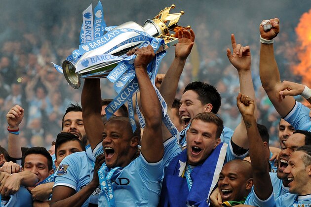 Manchester City's players captain Vincent Kompany, center, holds the Cup and celebrates with teammates after being crowned Premier League Champions, after the English Premier League soccer match between Manchester City and West Ham United at the Etihad Stadium,  Manchester, England, Sunday, May 11, 2014. (AP Photo/Rui Vieira)