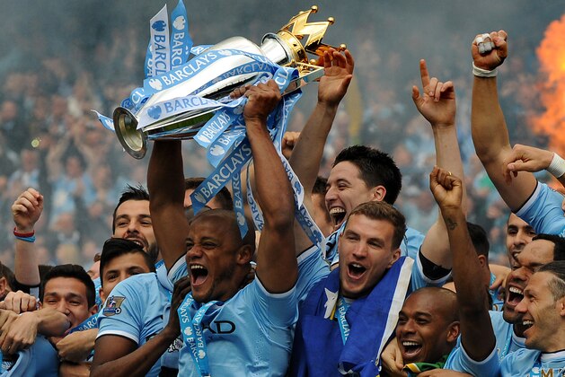 Manchester City's players captain Vincent Kompany, center, holds the Cup and celebrates with teammates after being crowned Premier League Champions, after the English Premier League soccer match between Manchester City and West Ham United at the Etihad Stadium,  Manchester, England, Sunday, May 11, 2014. (AP Photo/Rui Vieira)