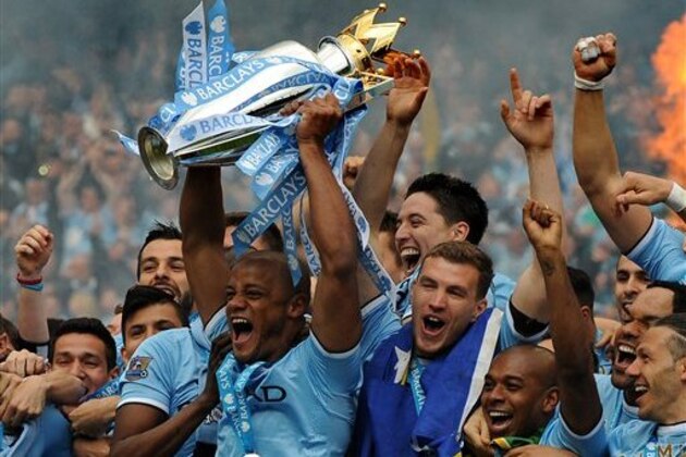 Manchester City's players captain Vincent Kompany, center, holds the Cup and celebrates with teammates after being crowned Premier League Champions, after the English Premier League soccer match between Manchester City and West Ham United at the Etihad Stadium,  Manchester, England, Sunday, May 11, 2014. (AP Photo/Rui Vieira)