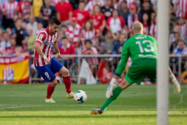 MADRID, SPAIN - MAY 11:  David Villa (L) of Atletico de Madrid strikes the ball against goalkeeper Willy Caballero (R) of Malaga CF during the La Liga match between Club Atletico de Madrid and Malaga CF at Vicente Calderon Stadium on May 11, 2014 in Madrid, Spain.  (Photo by Gonzalo Arroyo Moreno/Getty Images)