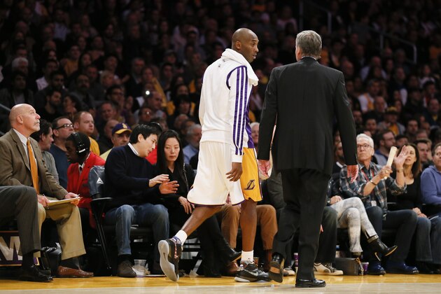 Los Angeles Lakers' Kobe Bryant walks to go into the game as he talks with head coach Mike D'Antoni  against the Toronto Raptors during the second half of an NBA basketball game in Los Angeles, Sunday, Dec. 8, 2013. It was Bryant's first game back after a torn left Achilles tendon injury on April 12th and the Raptors won 106-94. (AP Photo/Danny Moloshok)