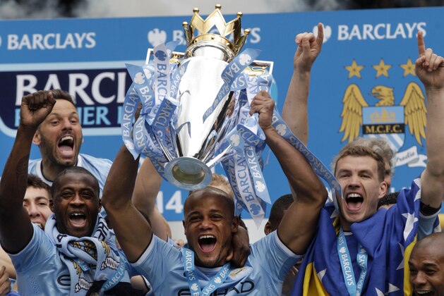 Manchester City's Vincent Kompany raises the trophy after the English Premier League soccer match between Manchester City and West Ham at the Etihad Stadium in Manchester, England, Sunday May 11, 2014.  Manchester City won the Premier League for the second time in three seasons on Sunday, completing its campaign with a comfortable 2-0 victory over West Ham that lacked any of the drama of its previous title.  (AP Photo/Jon Super)