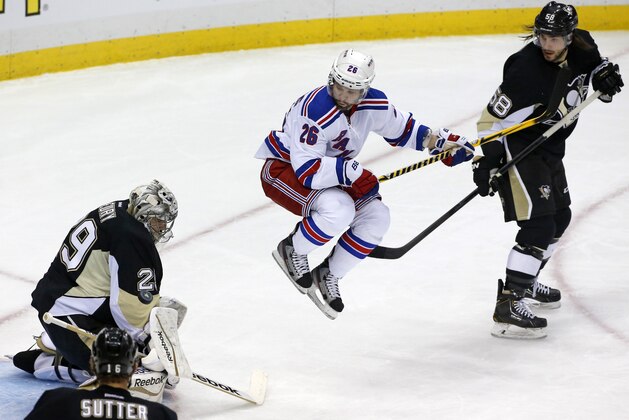 New York Rangers' Martin St. Louis (26) leaps out of the way of a shot between Pittsburgh Penguins goalie Marc-Andre Fleury (29) and Kris Letang (58) in the first period of Game 2 of a second-round NHL playoff hockey series in Pittsburgh, Sunday, May 4, 2014. Penguins' Fleury blocked the shot (AP Photo/Gene J. Puskar)