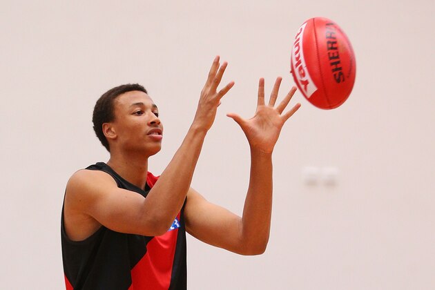 MELBOURNE, AUSTRALIA - FEBRUARY 14:  Young Australian basketball player Dante Exum marks the ball after being presented a jumper by Joe Daniher of the Bombers during an Essendon Bombers AFL media session at True Value Solar Centre on February 14, 2014 in Melbourne, Australia.  (Photo by Michael Dodge/Getty Images)