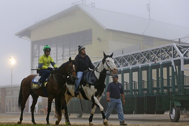 Kid Cruz, left, with exercise rider Reul Munoz aboard, walks past the grandstand after a workout under a thick layer of fog at Pimlico Race Course in Baltimore, Thursday, May 15, 2014. The Preakness Stakes horse race is scheduled to take place May 17. (AP Photo/Patrick Semansky)