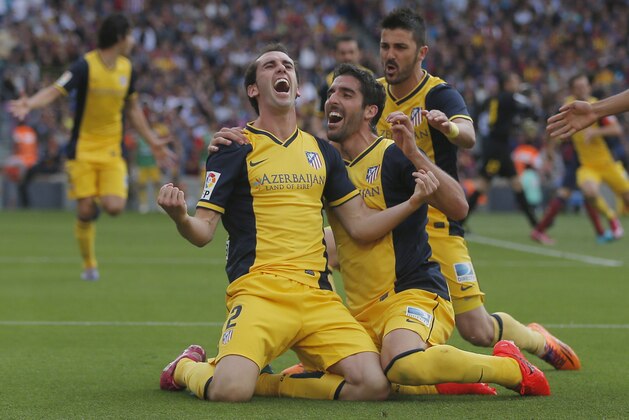 Atletico's Diego Godin from Uruguay, left, celebrates with teammates after scoring his side's first goal during a Spanish La Liga soccer match between FC Barcelona and Atletico Madrid at the Camp Nou stadium in Barcelona, Spain, Saturday, May 17, 2014. (AP Photo/Andres Kudacki)