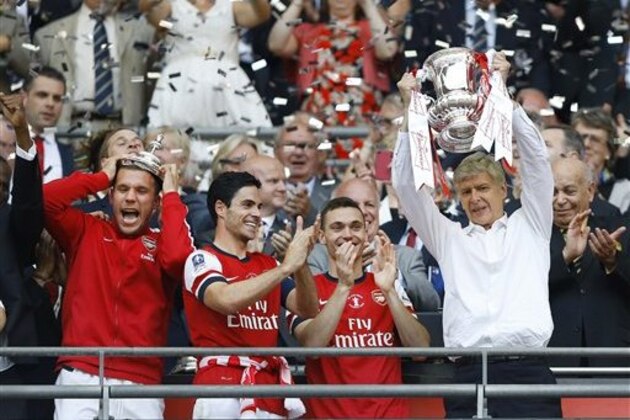 Arsenal's coach Arsene Wenger, right, hold the trophy aloft as he celebrates after his team won the English FA Cup final soccer match between Arsenal and Hull City at Wembley Stadium in London, Saturday, May 17, 2014. Arsenal won 3-2 after extra-time. (AP Photo/Kirsty Wigglesworth)