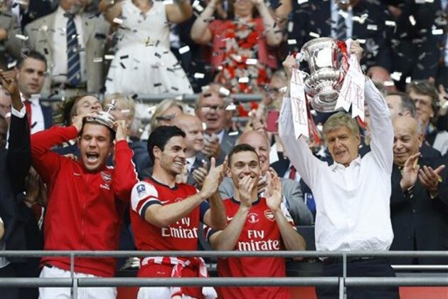 Arsenal's coach Arsene Wenger, right, hold the trophy aloft as he celebrates after his team won the English FA Cup final soccer match between Arsenal and Hull City at Wembley Stadium in London, Saturday, May 17, 2014. Arsenal won 3-2 after extra-time. (AP Photo/Kirsty Wigglesworth)