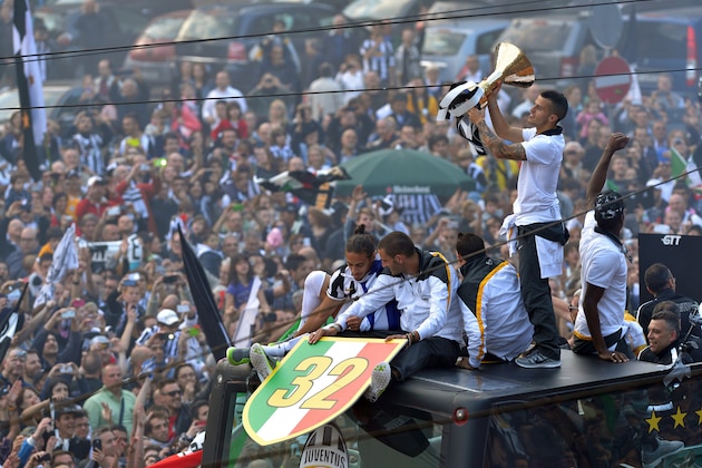 Juventus' players stand on a bus parading in downtown Turin, Italy, as they celebrate at the end of a Serie A soccer match between Juventus and Cagliari, Sunday, May 18, 2014. Juventus celebrated its third straight Serie A title with a 3-0 home victory over Cagliari to set a new European record of 102 points. Antonio Conte's side had already broken the Serie A points record but ensured it moved into triple figures by also becoming the first Italian side to maintain a 100% home record. (AP Photo/Massimo Pinca)