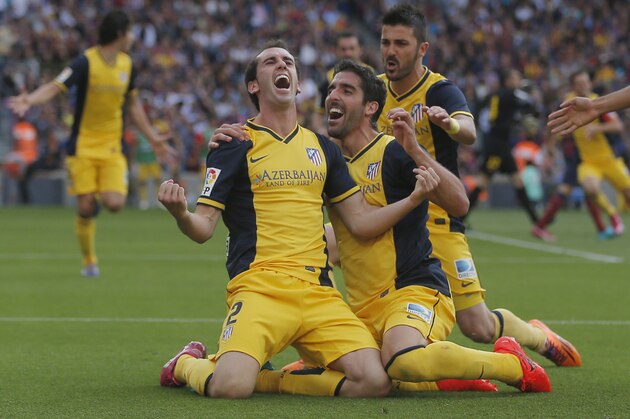 Atletico's Diego Godin from Uruguay, left, celebrates with teammates after scoring his side's first goal during a Spanish La Liga soccer match between FC Barcelona and Atletico Madrid at the Camp Nou stadium in Barcelona, Spain, Saturday, May 17, 2014. (AP Photo/Andres Kudacki)