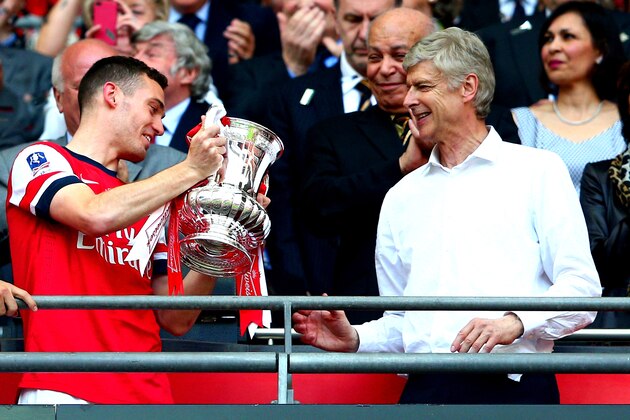 LONDON, ENGLAND - MAY 17:  Captain Thomas Vermaelen of Arsenal passes the trophy to Arsene Wenger manager of Arsenal (R) after the FA Cup with Budweiser Final match between Arsenal and Hull City at Wembley Stadium on May 17, 2014 in London, England.  (Photo by Clive Mason/Getty Images)