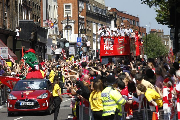 Arsenal's soccer team players parade through the street of London Sunday, May 18, 2014, aboard an open top bus in celebration of their English FA Cup win. Aaron Ramsey scored in extra time to clinch a 3-2 victory over Hull on Saturday, making Arsenal FA Cup Winners for the fifth time in Arsene Wenger's 14-year  tenure as coach of The Gunners.(AP Photo/Sang Tan)