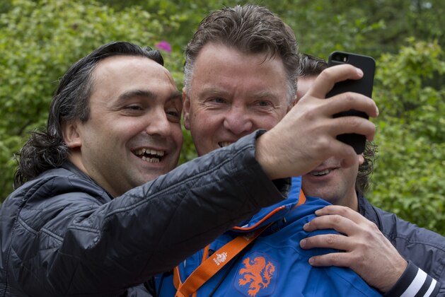 Twin brother Mustafa Bilgi, left, and Hasan, right, pose for a 'selfie' with Louis van Gaal, coach of the Dutch national soccer team in Hoenderloo, eastern Netherlands, Thursday, May 15, 2014. The 62-year-old coach, who is widely expected to be the manager of Manchester United next season, has been experimenting in recent days with a new formation which he says may sound more defensive, but will be executed according to the