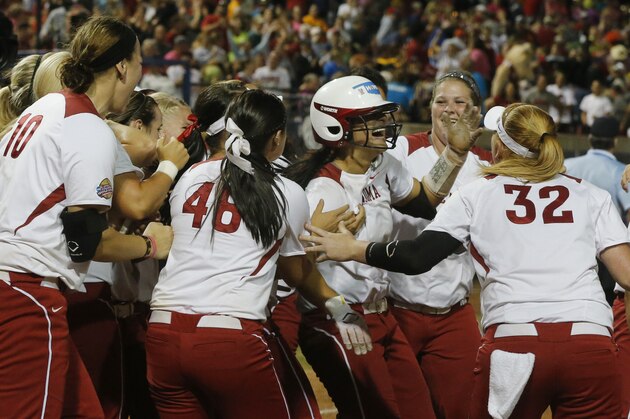 Oklahoma infielder Lauren Chamberlain, in center with batting helmet, is mobbed by her teammates following her 12th inning home run against Tennessee in the first game of the best of three Women's College World Series NCAA softball championship series in Oklahoma City, Monday, June 3, 2013. Oklahoma won 5-3 in 12 innings.(AP Photo/Sue Ogrocki)