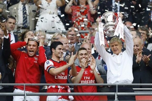 Arsenal's coach Arsene Wenger, right, hold the trophy aloft as he celebrates after his team won the English FA Cup final soccer match between Arsenal and Hull City at Wembley Stadium in London, Saturday, May 17, 2014. Arsenal won 3-2 after extra-time. (AP Photo/Kirsty Wigglesworth)