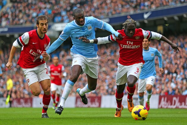MANCHESTER, ENGLAND - DECEMBER 14:  Yaya Toure of Manchester City is closed down by Mathieu Flamini and Bacary Sagna of Arsenal  during the Barclays Premier League match between Manchester City and Arsenal at Etihad Stadium on December 14, 2013 in Manchester, England.  (Photo by Clive Brunskill/Getty Images)