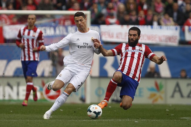Real's Cristiano Ronaldo, left, in action with Atletico's Arda Turan, right , during a Spanish La Liga soccer match between Atletico de Madrid and Real Madrid at the Vicente Calderon stadium in Madrid, Spain, Sunday, March 2, 2014. (AP Photo/Gabriel Pecot)