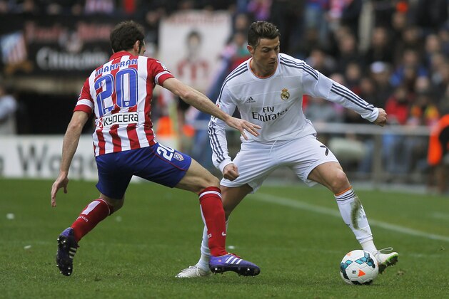 Atletico's Juanfran, left, in action with Real's Cristiano Ronaldo, right,  during a Spanish La Liga soccer match between Atletico de Madrid and Real Madrid at the Vicente Calderon stadium in Madrid, Spain, Sunday, March 2, 2014. (AP Photo/Andres Kudacki)