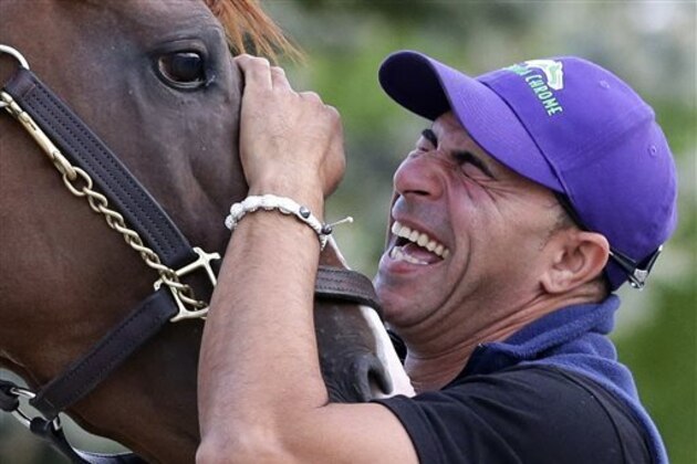 Exercise rider Willie Delgado laughs as he waits to guide Kentucky Derby and Preakness winner California Chrome onto a trailer at Pimlico Race Course in Baltimore, Tuesday, May 20, 2014.  The horse is headed to Belmont Park in Elmont, N.Y, where the Belmont Stakes horse race is scheduled to take place June 7. (AP Photo/Patrick Semansky)