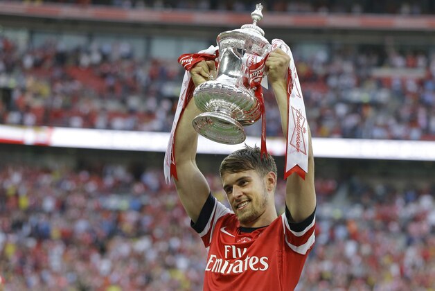 Arsenal's Aaron Ramsey holds the trophy aloft as he celebrates after his team won the English FA Cup final soccer match between Arsenal and Hull City at Wembley Stadium in London, Saturday, May 17, 2014. Arsenal won 3-2 after extra-time. (AP Photo/Kirsty Wigglesworth)