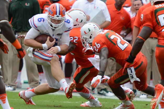 Sep 7, 2013; Miami Gardens, FL, USA; Florida Gators quarterback Jeff Driskel (6) is tackled by Miami Hurricanes defensive back Rayshawn Jenkins (26) and  Kacy Rodgers (22) during the first half of the game at Sun Life Stadium. Mandatory Credit: Brad Barr-USA TODAY Sports