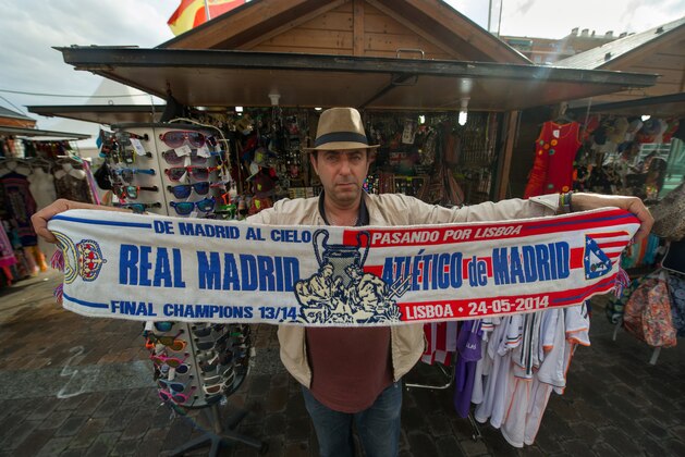 MADRID, SPAIN - MAY 20:  Eusebio Trujillo holds up a Real Madrid and Atletico de Madrid scarf for the UEFA Champions League final at his outdoor stall on May 20, 2014 in Madrid, Spain. Real Madrid CF play cross-town rivals Club Atletico de Madrid in the final on May 24 in Lisbon, Porgugal. (Photo by Denis Doyle/Getty Images)