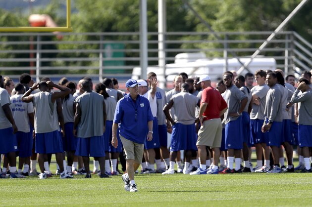 New York Giants head coach Tom Coughlin, center, walks away as the team huddles after stretching during NFL football training camp in East Rutherford, N.J., Friday, July 26, 2013. (AP Photo/Julio Cortez)