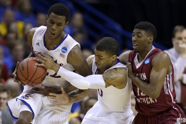 Kansas' Frank Mason, center, tries to hand a ball to teammate Andrew Wiggins, left, as Eastern Kentucky's Marcus Lewis watches during the first half of a second-round game in the NCAA college basketball tournament Friday, March 21, 2014, in St. Louis. (AP Photo/Jeff Roberson)