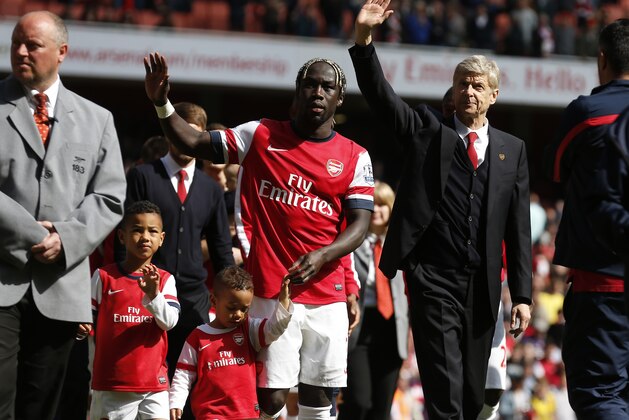 Arsenal's manager Arsene Wenger, center right, and Bacary Sagna, center left, wave to the supporters as the team parade around the stadium in their last home match of the season, after their English Premier League soccer match against West Bromwich Albion at Emirates Stadium in London, Sunday, May 4, 2014. (AP Photo/Sang Tan)