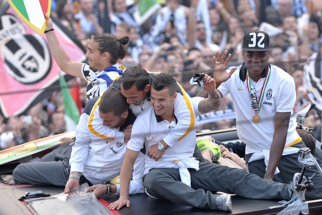 Juventus' players stand on a bus parading in downtown Turin, Italy, as they celebrate at the end of a Serie A soccer match between Juventus and Cagliari, Sunday, May 18, 2014. Juventus celebrated its third straight Serie A title with a 3-0 home victory over Cagliari to set a new European record of 102 points. Antonio Conte's side had already broken the Serie A points record but ensured it moved into triple figures by also becoming the first Italian side to maintain a 100% home record. (AP Photo/Massimo Pinca)