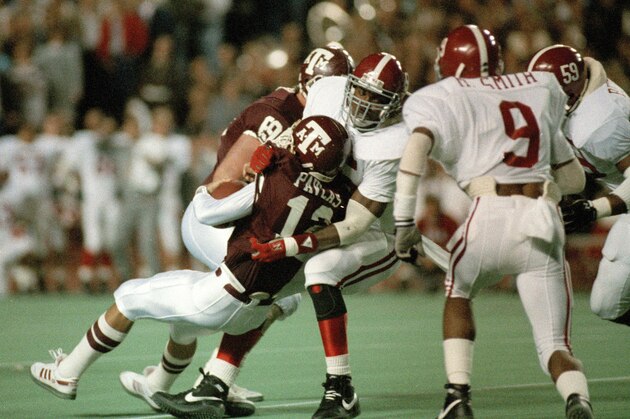 Texas A&M quarterback Lance Pavlas (12) is sacked for a 4-yard loss by Derrick Thomas (55) of the Alabama Crimson Tide, Dec. 1, 1988. The action is from the first period of the game, dubbed the