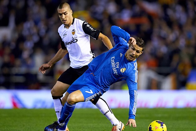 VALENCIA, SPAIN - DECEMBER 22:  Oriol Romeu (L) of Valencia competes for the ball with Cristiano Ronaldo of Real Madrid during the La Liga match between Valencia CF and Real Madrid CF at Estadio Mestalla on December 22, 2013 in Valencia, Spain.  (Photo by Manuel Queimadelos Alonso/Getty Images)