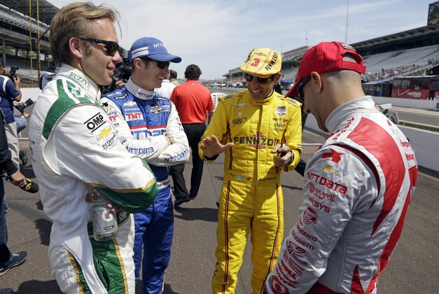 Helio Castroneves, of Brazil, right center, tells a story to fellow drivers Ed Carpenter, left, Ryan Briscoe, of Australia, left center, and Tony Kanaan, of Brazil, before the start of practice for the Indianapolis 500 IndyCar auto race at the Indianapolis Motor Speedway in Indianapolis, Monday, May 19, 2014. (AP Photo/Michael Conroy)