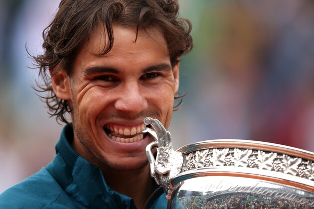 PARIS, FRANCE - JUNE 09:  Rafael Nadal of Spain bites the Coupe des Mousquetaires trophy as he celebrates after the men's singles final against David Ferrer of Spain during day fifteen of the French Open at Roland Garros on June 9, 2013 in Paris, France.  (Photo by Clive Brunskill/Getty Images)