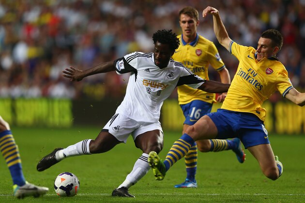SWANSEA, WALES - SEPTEMBER 28:  Wilfried Bony (L) of Swansea City pulls the trigger as Laurent Koscielny (R) of Arsenal attempts to block the shot during the Barclays Premier League match between Swansea City and Arsenal at the Liberty Stadium on September 28, 2013 in Swansea, Wales.  (Photo by Michael Steele/Getty Images)