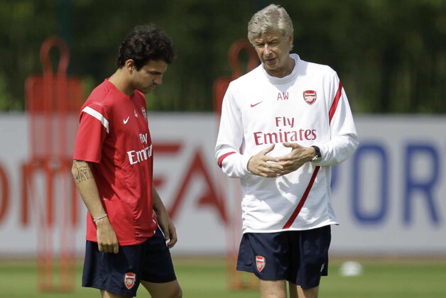 Arsenal's Cesc Fabregas, left, talks to his French manager Arsene Wenger at the start of a training session at the club's facilities in London Colney, England, Friday, Aug. 5, 2011.  The new English Premier League season starts on August 13 and it has been another offseason of unsettling speculation for Arsenal about whether captain Cesc Fabregas will return to Barcelona.  (AP Photo/Matt Dunham)