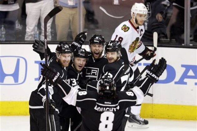 Los Angeles Kings' Jeff Carter (77), Tyler Toffoli (73), Jake Muzzin (6), Dustin Brown (23) and Drew Doughty (8) celebrate a goal by Muzzin as Chicago Blackhawks' Jonathan Toews (19) skates behind them during the first period of Game 4 of the Western Conference finals of the NHL hockey Stanley Cup playoffs on Monday, May 26, 2014, in Los Angeles. (AP Photo/Jae C. Hong)