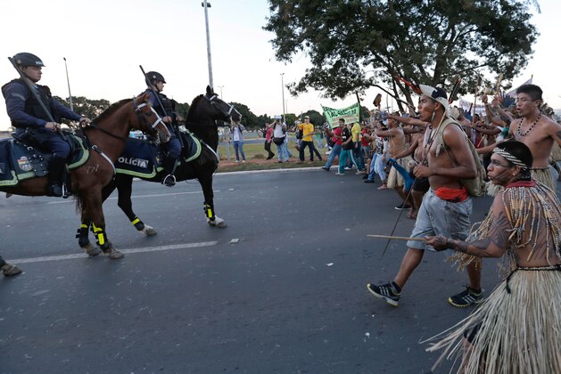 Indigenous protesters in traditional headdress clash with military police during a protest against FIFA World Cup outside the National Stadium in Brasilia, Brazil, Tuesday, May 27, 2014. Brazil's indigenous communities calling for the federal court to demarcate indigenous lands are also protesting against the 2014 FIFA World Cup that starts in June. (AP Photo/Eraldo Peres)