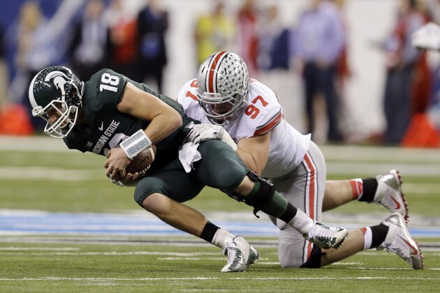 FILE - In this Dec. 7, 2013 file photo, Michigan State's Connor Cook (18) is sacked by Ohio State's Joey Bosa (97) during the first half of a Big Ten Conference championship NCAA college football game in Indianapolis. With Bosa, Noah Spence, Adolphus Washington and Michael Bennett up front and quality players behind them, the Buckeyes are hoping to erase the memory of a porous final few games in the 2013 season. (AP Photo/Darron Cummings, File)