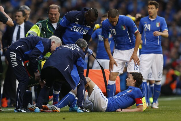 Italy's Riccardo Montolivo, lower right, is being treated after gettimg injured from a tackle during their international friendly soccer match at Craven Cottage, London, Saturday, May 31, 2014. (AP Photo/Sang Tan)