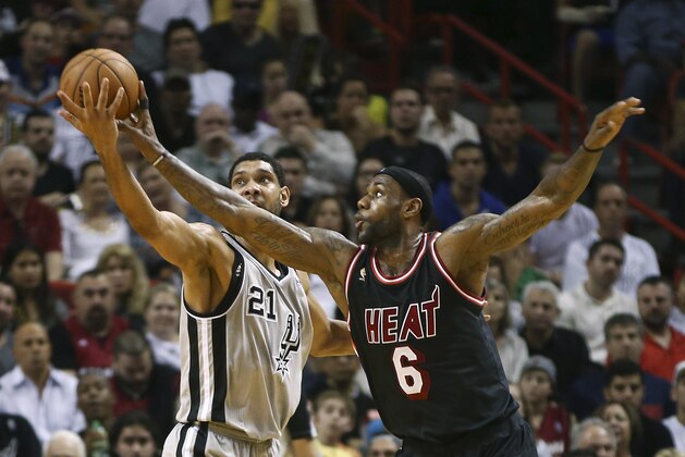Miami Heat's LeBron James (6) fouls San Antonio Spurs' Tim Duncan (21) as he tries to steal the ball during the second half of an NBA basketball game in Miami, Sunday, Jan. 26, 2014. The Heat won 113-101. (AP Photo/J Pat Carter)