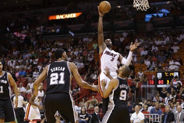 Miami Heat's Dwyane Wade (3) shoots over San Antonio Spurs' Tim Duncan (21) and Tony Parker (9) during the second half of an NBA preseason basketball game, Saturday, Oct. 19, 2013, in Miami. The Heat defeated the Spurs 121-96. (AP Photo/Lynne Sladky)