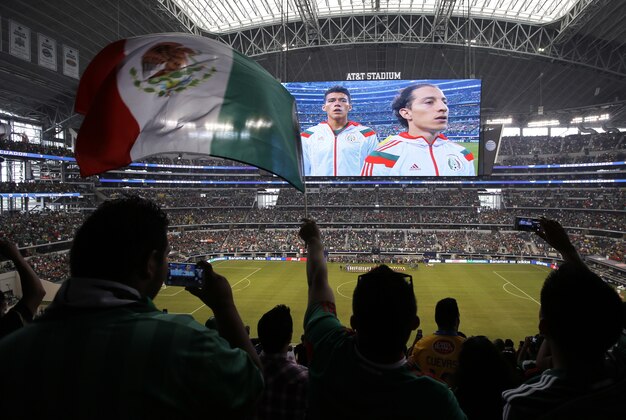 Mexico fans wave a national flag during the playing of their country's national anthem before a friendly soccer match against Ecuador, Saturday, May 31, 2014, in Arlington, Texas.  (AP Photo/Tony Gutierrez)