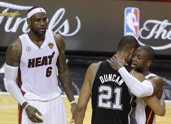 The San Antonio Spurs' Tim Duncan (21) embraces Miami Heat's Dwyane Wade (3) as Miami Heat's LeBron James (6) looks on during the first half in Game 7 of the NBA basketball championship, early Friday morning, June 21, 2013, in Miami. The Miami Heat defeated the San Antonio Spurs 95-88 to win their second straight NBA championship. (AP Photo/Steve Mitchell, Pool)