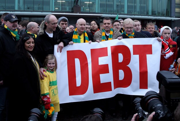 MANCHESTER, ENGLAND - JANUARY 23:  Manchester United fans, wearing green and gold scarves, protest against the Glazers, current owners of Manchester United before the Barclays Premier League match between Manchester United and Hull City at Old Trafford on January 23, 2010 in Manchester, England.  (Photo by Julian Finney/Getty Images)