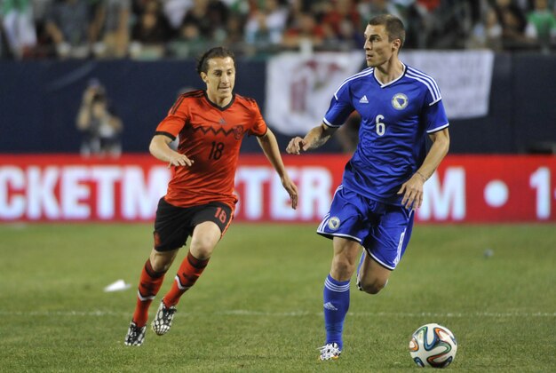 Jun 3, 2014; Chicago, IL, USA;  Mexico forward Andres Guardado (18) and Bosnia and Herzegovina defender Ognjen Vranjes (6) go for the ball during the second half at Soldier Field. Bosnia and Herzegovina defeated Mexico 1-0. Mandatory Credit: David Banks-USA TODAY Sports
