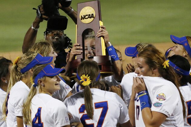 Florida pitcher Hannah Rogers holds the trophy as the team celebrates following an NCAA Women's College World Series softball tournament game against Alabama in Oklahoma City, Tuesday, June 3, 2014. Florida won the game 6-3 and took the title. (AP Photo/Sue Ogrocki)
