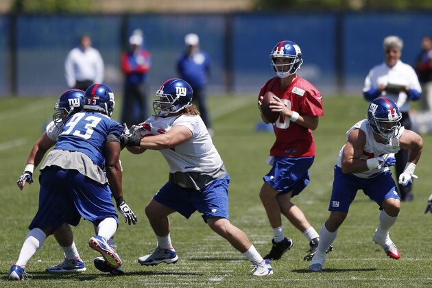 New York Giants quarterback Eli Manning, center, looks to pass during an NFL football organized team activity, Thursday, May 29, 2014, in East Rutherford, N.J. (AP Photo/Julio Cortez)